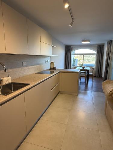 a kitchen with white cabinets and a dining room at City Stay B&B in Taʼ l-Imgħajjen
