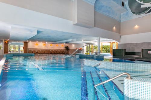 a large swimming pool with blue water at Apartamenty i pokoje Montana in Kudowa-Zdrój