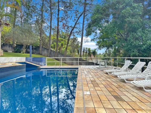 a swimming pool with white lounge chairs around it at Refúgio Natureza Piscina Sala de Jogos Lazer in Campo Limpo Paulista