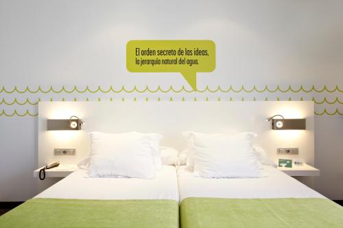 a bedroom with a bed with white sheets and green blankets at Hotel Costa Azul in Palma de Mallorca