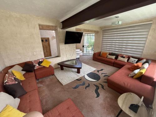 een woonkamer met rode banken en een televisie bij Casa Vista Hermosa in Tonatico