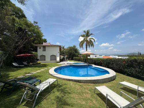 een zwembad in een tuin met stoelen en een palmboom bij Casa Vista Hermosa in Tonatico