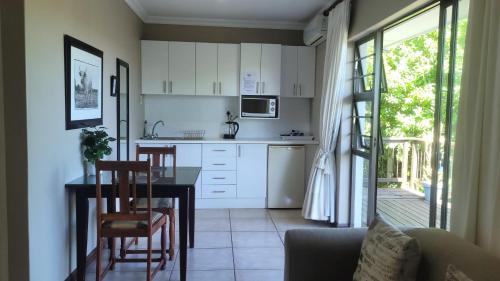 a kitchen with white cabinets and a table and chairs at Suite 14- Deja' Blu Bed and Breakfast- East London in East London