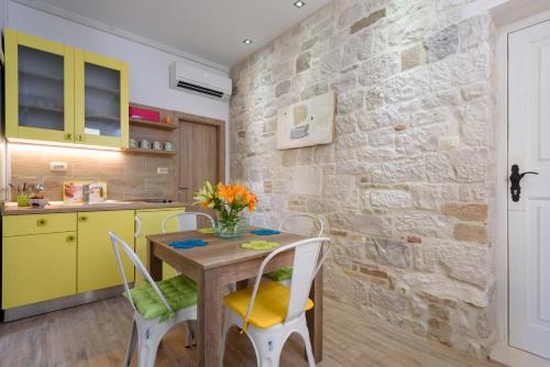 a kitchen with yellow cabinets and a wooden table and chairs at Apartments Kaja in Trogir