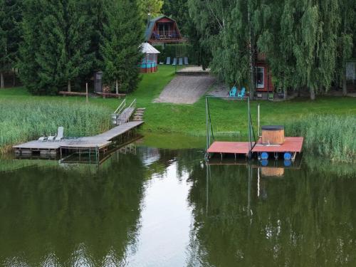 a couple of boats on a lake with a house at Sodyba Brazylija in Taraldžiai