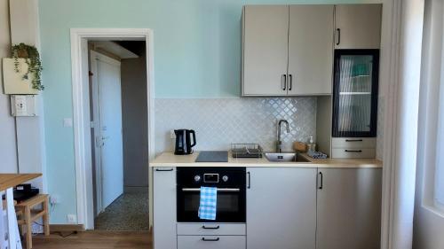 a kitchen with white cabinets and a stove top oven at Bleu Langrune - Studio vue Mer in Langrune-sur-Mer