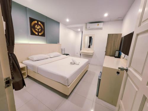 Un dormitorio con una cama blanca y un baño. en ALBADER HoTEL, en Patong Beach