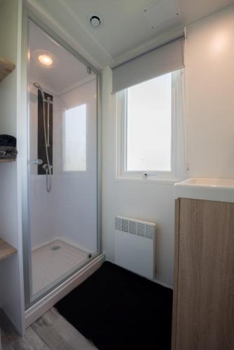a bathroom with a shower and a sink and a window at Camping Aux Rives du Soleil in Pont-de-Vaux