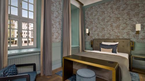 a bedroom with a bed and a chair and a window at Hotel Taschenbergpalais Kempinski in Dresden