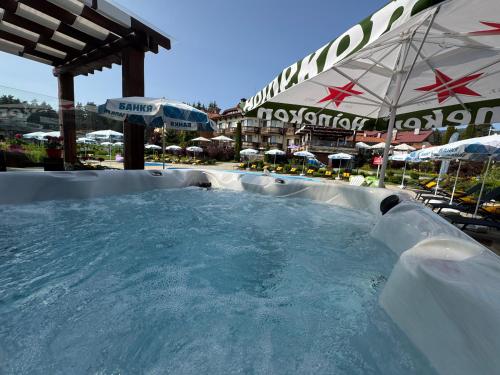 a large plunge pool in a resort with an umbrella at Family Hotel Eterno in Tsigov Chark