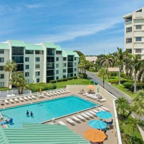 a pool with chairs and umbrellas in a resort at Excellent beach front community, golf course, tennis, sunny weather year round! in Fort Pierce