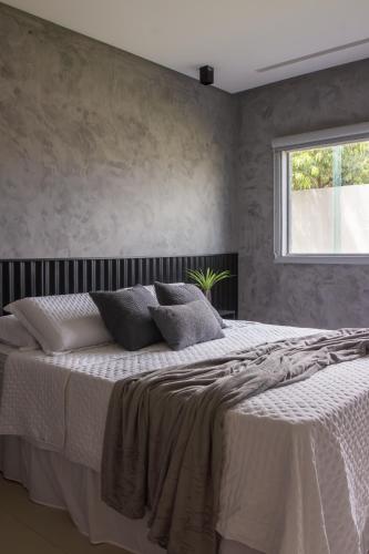 a bedroom with a large white bed with a window at Vila Piá 02 in Piaçabuçu