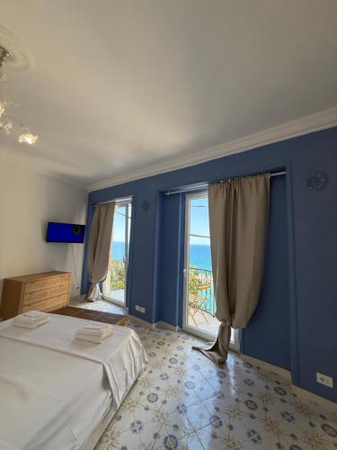 een slaapkamer met blauwe muren en een bed en ramen bij Dogana Apartment in Agropoli