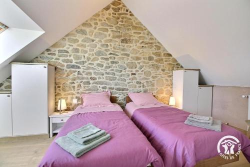 two beds in a room with a stone wall at Gîte Liorh & Tejtal - 11/12 pers in Plumergat
