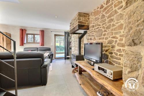 a living room with a tv and a stone wall at Gîte Liorh & Tejtal - 11/12 pers in Plumergat