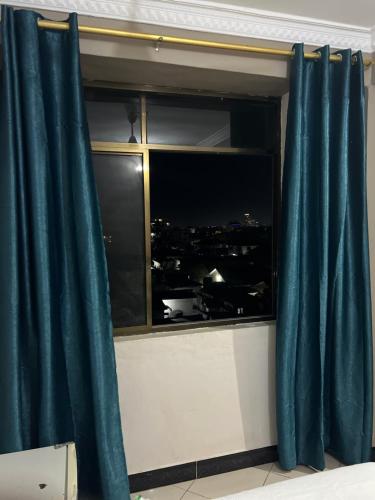 a window with blue curtains with a view of a city at Everlasting stays in Dar es Salaam