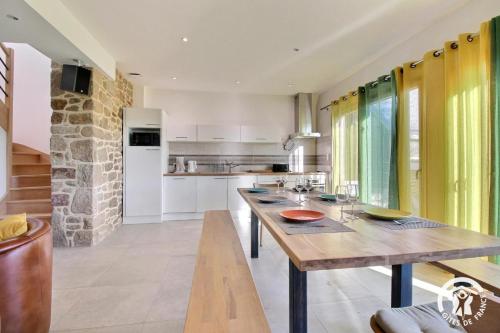 a kitchen with a wooden table and a stone wall at Gîte Le Liorh 5/6 pers in Plumergat
