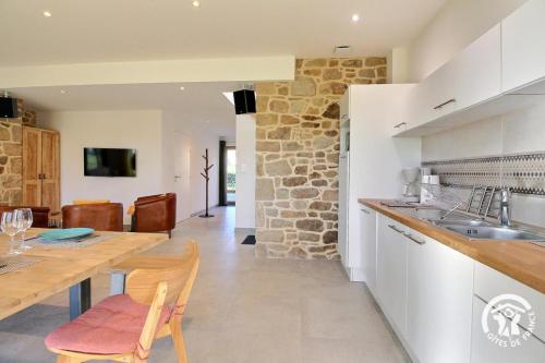 a kitchen and dining room with a stone wall at Gîte Le Liorh 5/6 pers in Plumergat