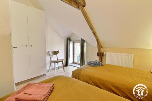 a bedroom with two beds and a chair at Gîte Le Liorh 5/6 pers in Plumergat
