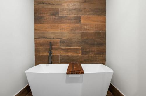 a bathroom with a white tub and a wooden wall at NEW CONDO Beach, Pool, Rain Forest & PGA Golf in Rio Grande