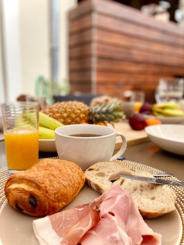 a table with a plate of food and a cup of orange juice at Magnifique maison de village in Saillenard