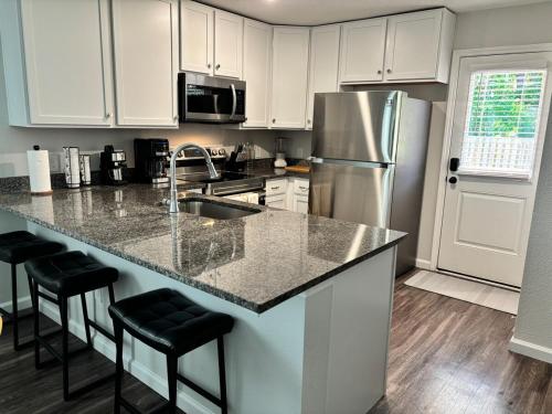 Una cocina con gabinetes blancos y un refrigerador de acero inoxidable. en The Old City Sunshine Retreat, en St. Augustine