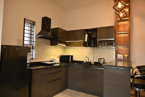 a kitchen with black cabinets and a black refrigerator at Tranquil Touch in Chikmagalūr