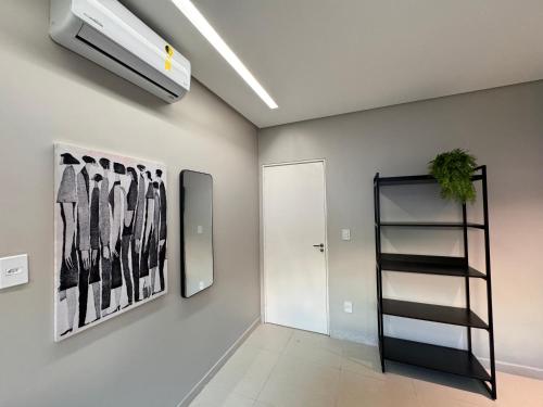 a hallway with a black shelf and paintings on the wall at Vila Piá 02 in Piaçabuçu