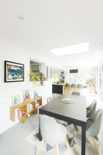 a dining room with a black table and white chairs at La parenthèse familiale in Saint-Cyr-sur-Loire