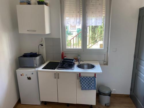 une petite cuisine avec un évier et une fenêtre dans l'établissement Sympathique logement en rez-de-chaussé, de 21m 2, à Beauvais