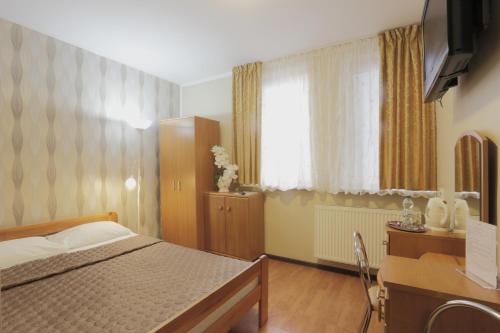 a bedroom with a bed and a desk and a window at Silver Budget in Białystok