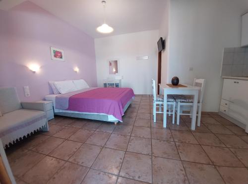 a bedroom with a bed and a table and a table and chairs at Ikos Studios and Apartments in Patitiri