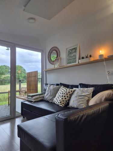 a living room with a black leather couch with pillows at Chalet Stockholm in Bleckede