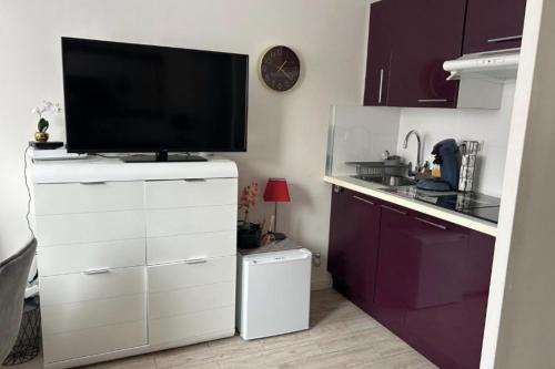 une cuisine avec une télévision au-dessus d'une armoire blanche dans l'établissement Studio At 200m From Beach Residence With Pool, à Cannes