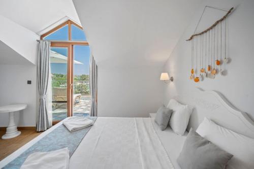 a white bedroom with a large bed and a window at Kumluk Hotel in Datca