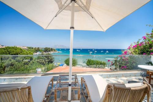 a table and chairs with an umbrella and the ocean at Kumluk Hotel in Datca
