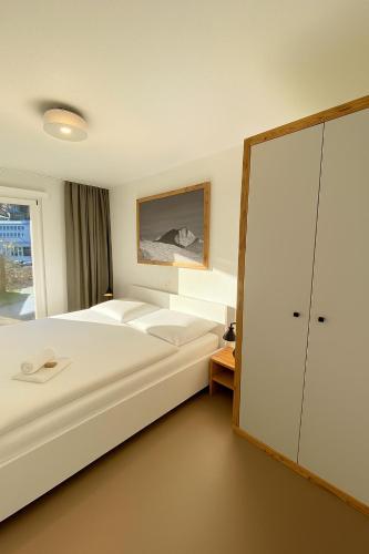 a bedroom with a large white bed and a closet at house & living junbi in Laax