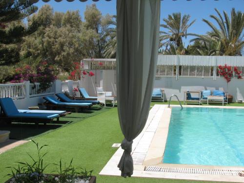 a pool with chaises and chairs next to at Dar Salem in Djerba