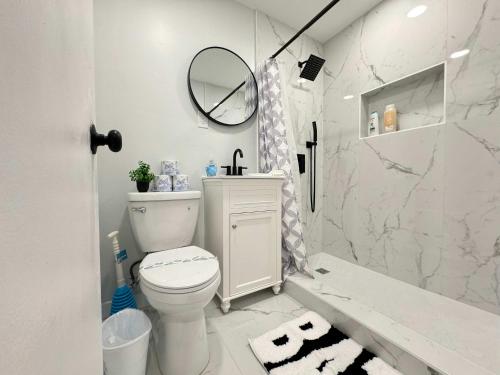 a white bathroom with a toilet and a mirror at Downtown New-Built Roof-top balcony City View 525Pkwy in Atlanta