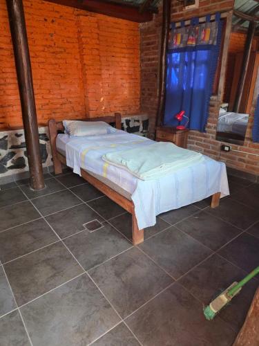 a bed in a room with a brick wall at alojamiento Villa sarita in Posadas