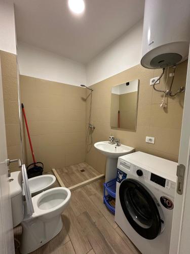a bathroom with a toilet and a sink and a washing machine at Casa Del Mar in Shëngjin