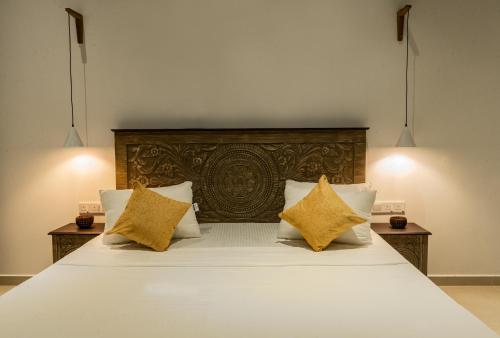 a bedroom with a large white bed with yellow pillows at The Smiling Leaf in Ambalangoda