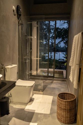 a bathroom with a toilet and a large window at The Smiling Leaf in Ambalangoda