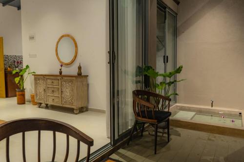 a room with a chair and a mirror and a dresser at The Smiling Leaf in Ambalangoda
