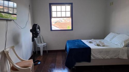 a bedroom with a bed with a fan and a window at Quarto Casal Simples in Mariana