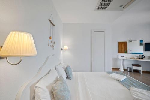 a white bedroom with a bed with a lamp at Kumluk Hotel in Datca