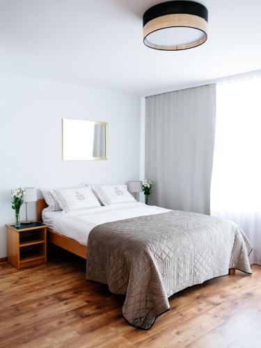 a white bedroom with a bed and a chandelier at Willa Ada Pokoje & Apartamenty in Karwia