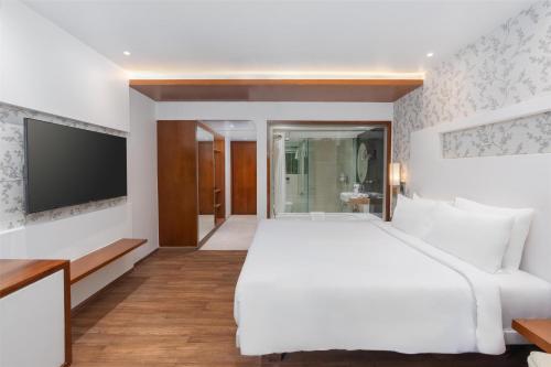 a bedroom with a white bed and a flat screen tv at Country Inn & Suites By Radisson Navi Mumbai in Navi Mumbai