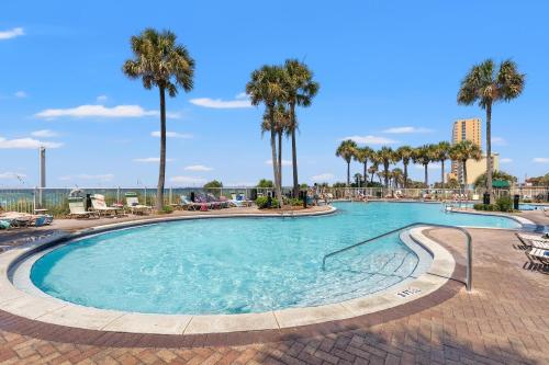 a large swimming pool with palm trees and chairs at Grand Panama by Panhandle Getaways in Panama City Beach