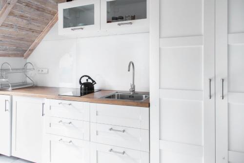 a kitchen with white cabinets and a sink at Apartament z tarasem in Stegna